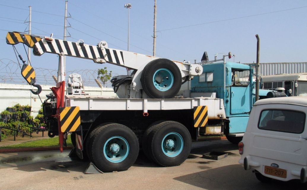 A light-blue heavy-duty tow truck with a boom crane